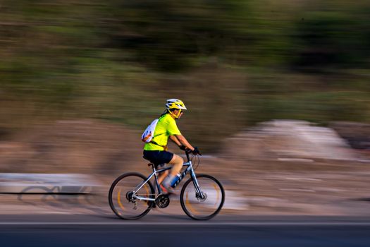 Pune, Maharashtra, India - October 4th, 2017 : Motion blur, panning image of a bicycle rider wearing helmet for safety./
