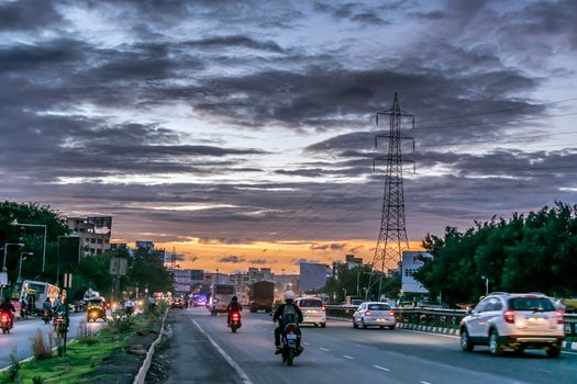Busy road with a background of nice monsoon clouds pattern and sunset in Pune city of Maharashtra, India.