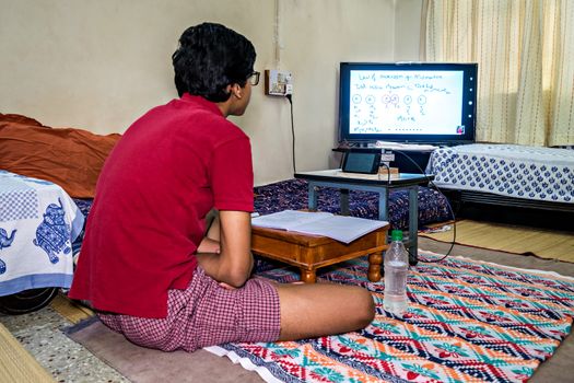 Pune,  India - June 2nd, 2020 : Student pursuing online education through cell phone  due to closed schools on account of spread of pandemic COVID-19, corona virus in Pune, Maharashtra, India.