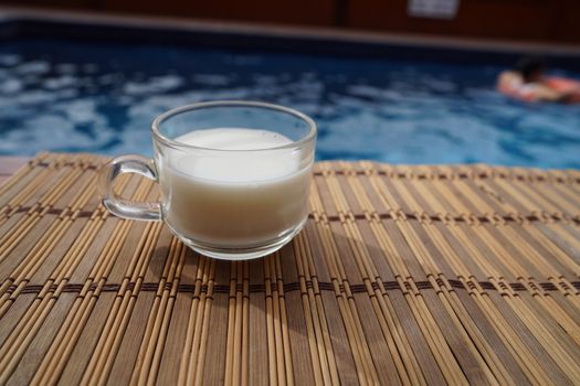 A cup of hot latte coffee is beside the pool in the house.