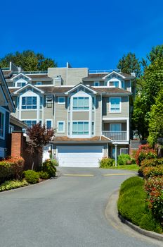 Asphalt driveway leading to complex of residential townhouses on bright sunny day