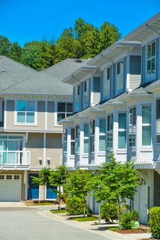 Facades of luxury residential townhouses with asphalt driveway in front