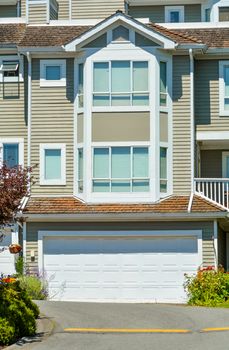 Front of residential townhouse with asphalt driveway on sunny day in Vancouver, Canada