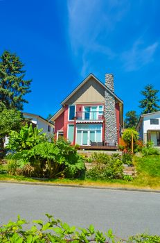 Beautiful suburban house with landscaped terrace and blue sky background. Residential house at sunny day in British Columbia