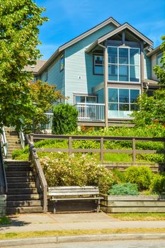 Facade of residential house built on land terrace with wooden bench in front