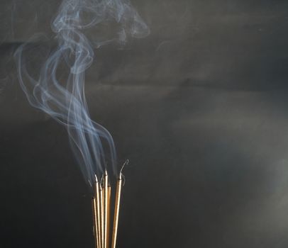 Incense burning incense, white smoke, black background, used as background image Paying homage to the sacred objects of the people of Buddhism according to their beliefs and beliefs.