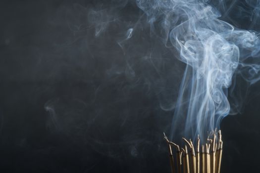 Incense burning incense, white smoke, black background, used as background image Paying homage to the sacred objects of the people of Buddhism according to their beliefs and beliefs.