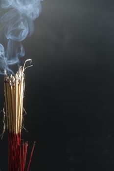 Incense burning incense, white smoke, black background, used as background image Paying homage to the sacred objects of the people of Buddhism according to their beliefs and beliefs.