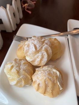 Breakfast cream-brown dessert. Icing Sugar is placed on a white plate.