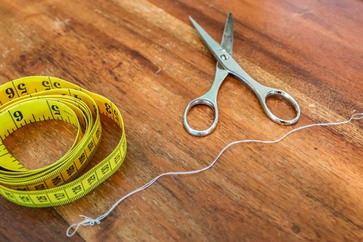 Different sewing accessoires on a brown wooden background. Sewing concept.