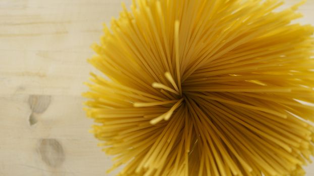 Top down flat lay view of a handful of spaghetti spoked spots that look like a yellow flower on a light wooden table background italian food cuisine copy space