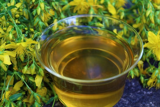 The picture shows a herb tea on an old weathered tree trunk