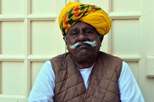 Jodhpur, Rajasthan, India, circa 2020. A sad old man cum gatekeeper wearing a yellow colorful turban with white mustache at the Mehrangarh Fort.