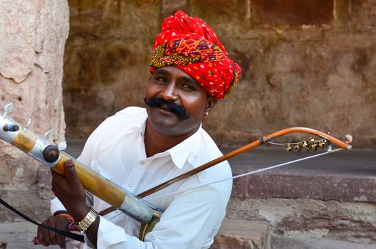 Jodhpur, Rajasthan, India, 2020. Closeup of Traditional Rajasthani sarangi player in his traditional dress and head gear turban red pagdi playing sarangi in Mehrangarh Fort.