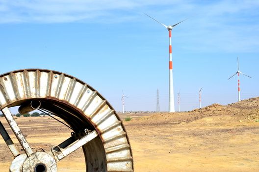 Windmills in the backdrop of a winding wheel on the way to Sam Sand Dunes (Thar Desert) from Jaisalmer, Rajasthan, India. The Jaisalmer Wind Park is India's 2nd largest operational onshore wind farm.
