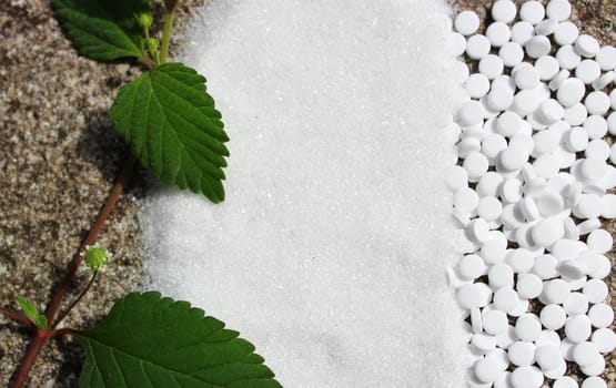 The picture shows a candy leaf, sugar and sweetener on a stone floor