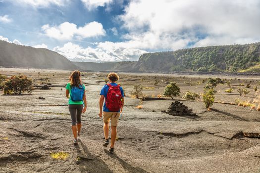 Couple tourists hikers walking on Kilauea Iki crater trail hike in Big Island, Hawaii. USA summer travel vacation destination for outdoor nature adventure, american tourism.