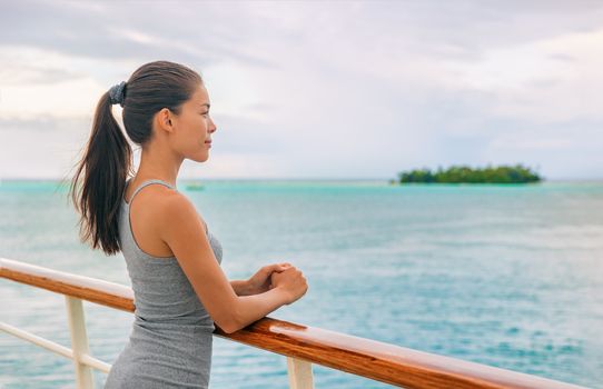 Cruise ship luxury Tahiti vacation island hopping French Polynesia Oceania world tour, in yacht on tropical ocean travel - Young tourist Asian woman watching sunset on deck of cruising boat.
