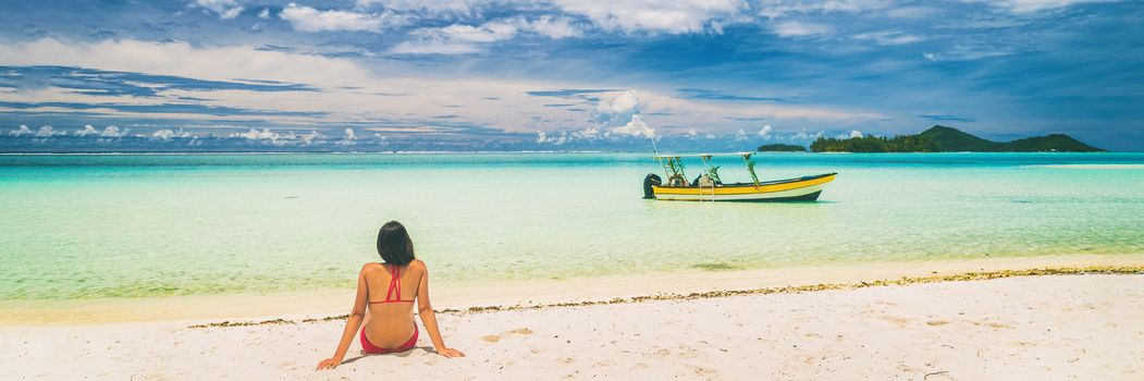 Luxury paradise getaway beach in French Polynesia. Secluded island boat tour in Tahiti, woman tourist relaxing sitting on sand looking at turquoise water banner panorama.