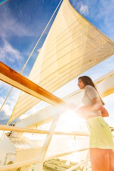 Luxury travel elegant woman on cruise ship yacht on jet set vacation sailing around the world. High end tourism sail boat in sunset.