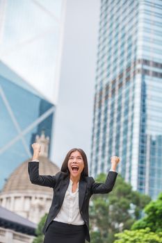 Business woman happy success in Hong Kong celebrating successful business with arms up hands raised in the air winning. Young multiracial Chinese Asian / Caucasian professional.