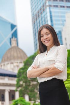 Happy confident young Asian business woman with arms crossed in urban city background, Hong Kong skyscrapers. Smiling businesswoman proud of working career, leader of success.