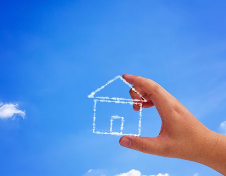 Home sweet home concept, hand holding cloud house on blue sky background