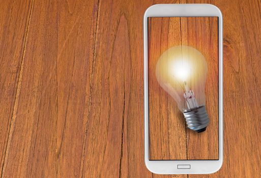 Idea and inspiration concept, business creativity, light bulb and mobile phone on wood background
