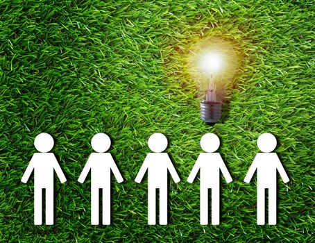 Think different concept, group of white paper people and light bulb on green grass background