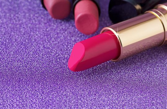 Red lipstick on purple background, cosmetic concept