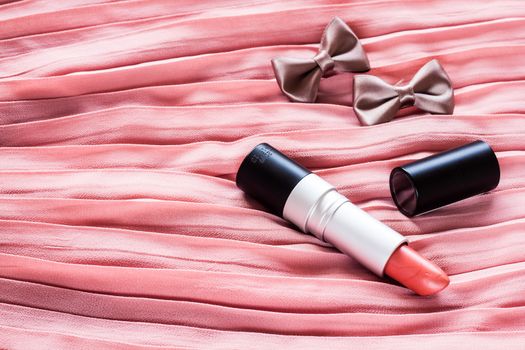 Tube of red lipstick on pink background