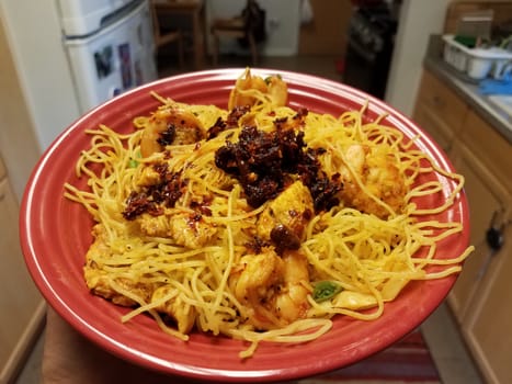 spicy Chinese noodles with chili sauce in red bowl in kitchen