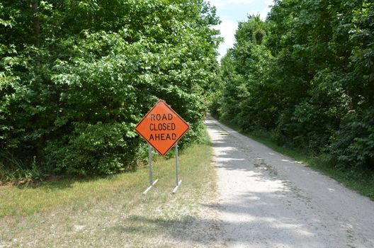 orange road closed ahead sign with path or trail