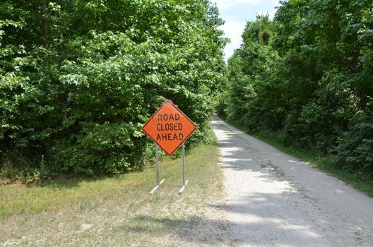 orange road closed ahead sign with path or trail