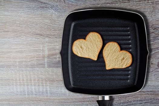 Two bread hearts and grilled pan on wood background, valentine day, romantic and love food concept