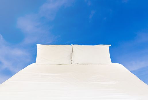 Clean bed on blue sky, relaxation and comfortable concept 