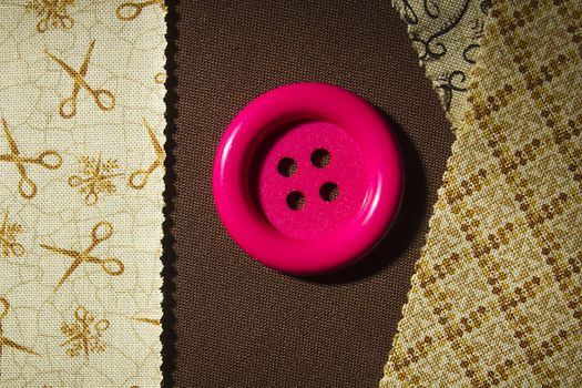 Button and fragments of fabric on a wooden table