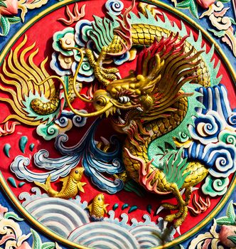 Golden dragon statue on the colorful wall in the temple