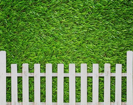 Security concept, white fence on green grass background, protection and safety