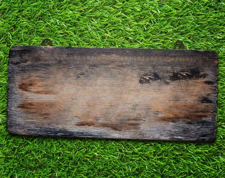 Old wood sign on green grass background, vintage and retro