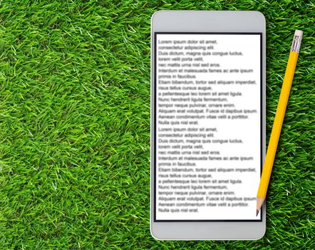 E-book, Electronic reading concept, internet content service, mobile phone and yellow pencil on green grass background