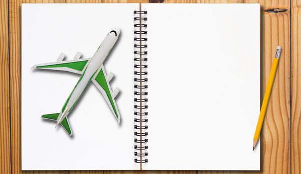 Travel concept, open notebook and yellow pencil on wooden table background
