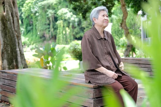 elder woman resting in garden. asian elderly female relaxing outdoors. senior leisure lifestyle