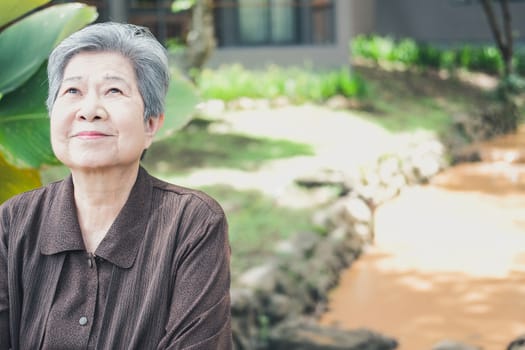elder woman resting in garden. asian elderly female relaxing outdoors. senior leisure lifestyle