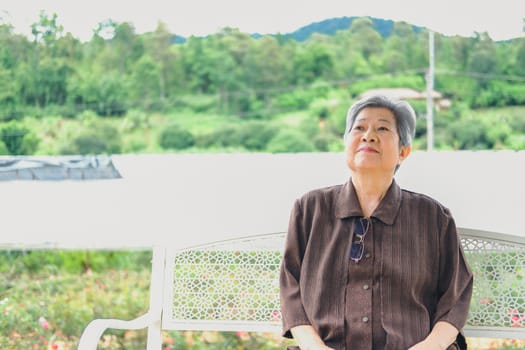elder woman resting in garden. asian elderly female relaxing outdoors. senior leisure lifestyle