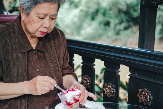 old asian elderly senior elder woman eating strawberry cream cheesecake at restaurant. mature retirement lifestyle
