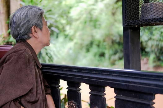 asian elder female woman resting relaxing on balcony terrace at home. elderly senior leisure lifestyle