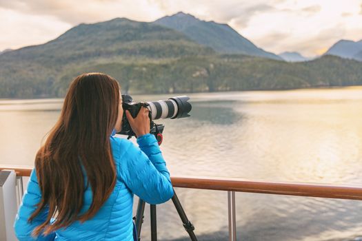 Travel photographer with professional telephoto lens camera on tripod shooting wildlife in Alaska, USA. Scenic cruising inside passage cruise tourist vacation adventure. Woman taking photo picture.