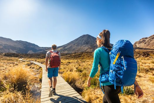 New Zealand Hiking Couple Backpackers Tramping At Tongariro National Park. Male and female hikers hiking by Mount Ngauruhoe. People living healthy active lifestyle outdoors.