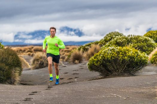 Trail run man athlete runner running marathon in desert landscape mountain hills summer background. Fitness and sports lifestyle.